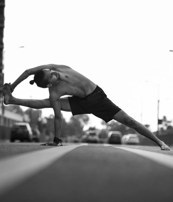 Man in a focused strength pose, showing control and balance in a minimalist setting.
